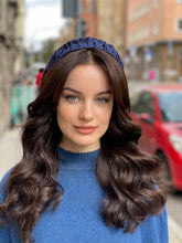 Load image into Gallery viewer, Navy ruffled headband worn over long dark waves, shown in a close outdoor portrait with a blue jumper.