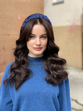 Load image into Gallery viewer, Navy ruffled headband worn over long dark waves, shown front-facing with a blue jumper against a stone wall.
